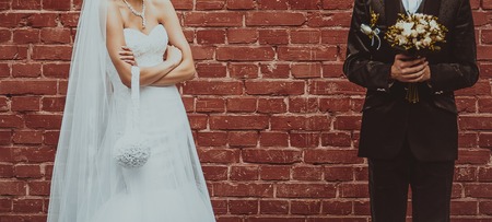 Groom and Bride embracing next to red brick wall. Hands of newlyweds  together. Wedding Couple.の写真素材
