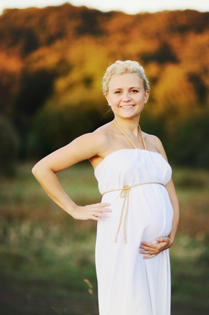 Portrat of  young pregnant woman in a white greek dress outside.の写真素材