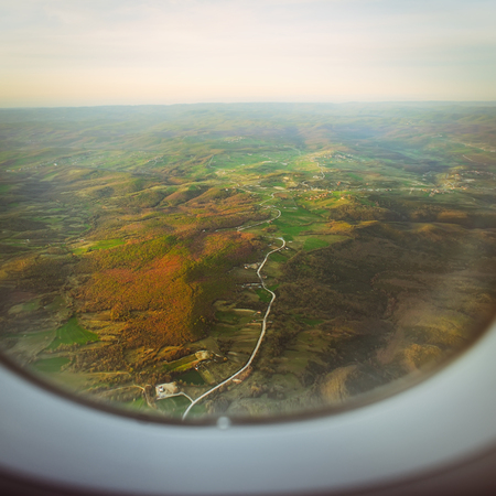 looking through airplane illuminator in the sunrise lightの写真素材