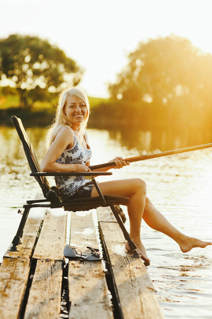 Young caucasian woman fishing at the lakeの写真素材