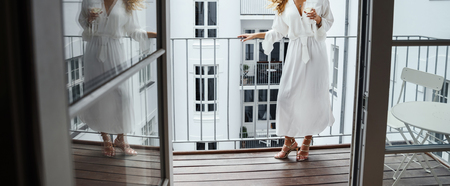Beautiful bride posing on the balcony in the long wedding dressの写真素材
