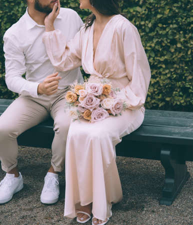 Bridal couple kissing on a bench. Beautiful bride with a bouqet.の写真素材