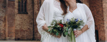 Newlywed lesbian couple on their happy wedding day wearing white dresses. Equality concept.の写真素材
