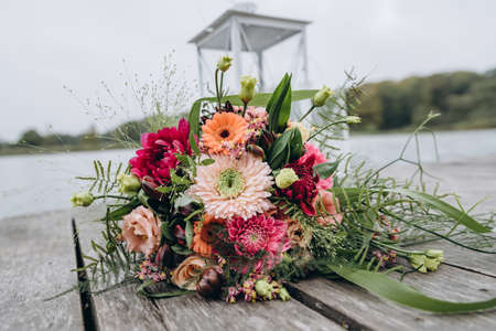 Gorgeous wedding bouquet and white candle lamps on a wooden pier.の写真素材