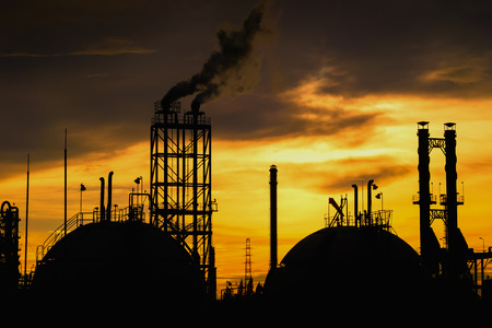 Gas storage sphere tanks and smoke stacks in silhouette image on sunset sky backgroundの写真素材
