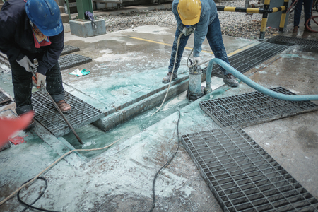 Contractor cleaning chemical drain in industrial plant