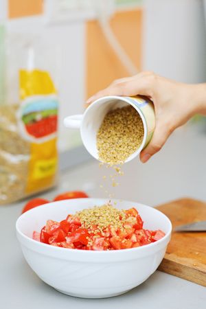 Pouring bulghur over chopped tomatoes for taboulehの写真素材