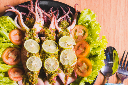top view of squid , octopus  topped with  spicy seafood sauce on brown wood tableの写真素材