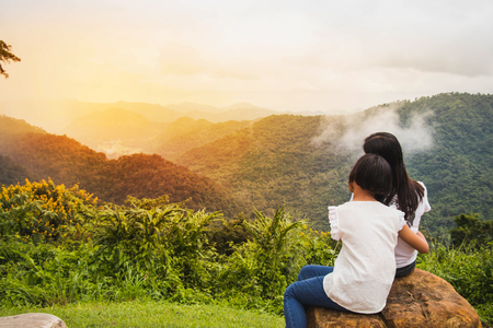 women sitting on the rock looking the nature with happiness in the morning.mother and daughter siting for  relax in the mountain.の写真素材