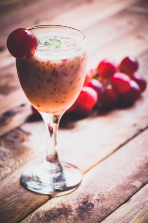 a glass of grape juice on the brown wood table with some grape beside for background.の写真素材