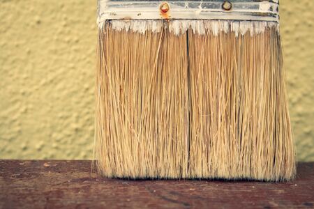 View of the bristles in a paint brush placed against a wall