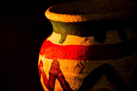 Handcrafted earthen pot again dark background. Clay vase made out of mud on dark background.の写真素材
