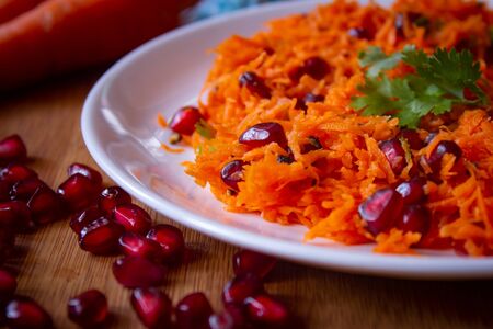 Salad of carrot and pomegranate seeds with cilantro topping. Healthy snack rich in antioxidants. Use for health concept.の写真素材