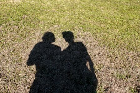Shadow of a woman and man in a green field. Shadow of a couple togetherの写真素材