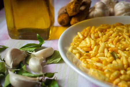 Spicy puffed rice (also known as muri, porri) in a plate with ginger, garlic, curry leaves. Muri is...