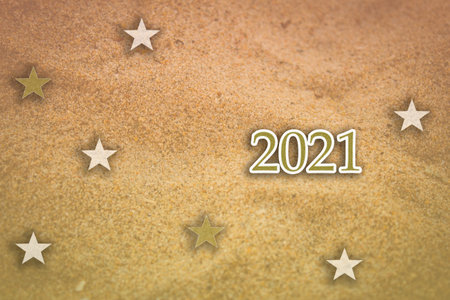 Happy New year 2021 concept use with stars and 2021 against a beach sand background.
