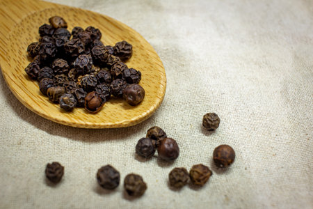 View of Black Peppercorns in a wooden spoon. Black pepper boost immunity naturally.の写真素材