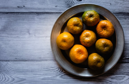 View of sweet oranges in a plate together. Kamala oranges on wooden background.