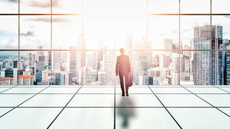 Businessman standing in a building looking at the cityの写真素材
