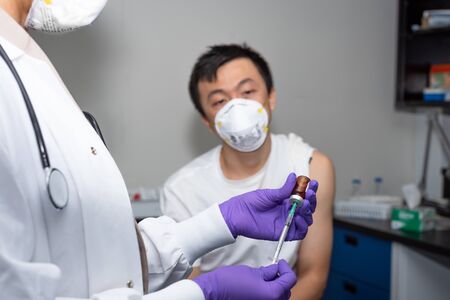 asian male receiving coronavirus treatment in clinicの写真素材
