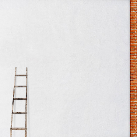weathered stucco wall, red brick frame with a wooden ladder backgroundの写真素材