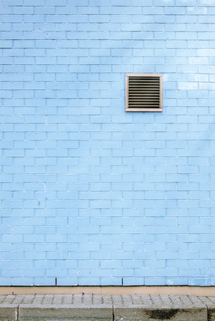 Ventilation grille on the blue brick wall, tiled floor, sun flaresの写真素材