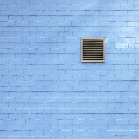 Ventilation grille on the blue brick wall, sun flares