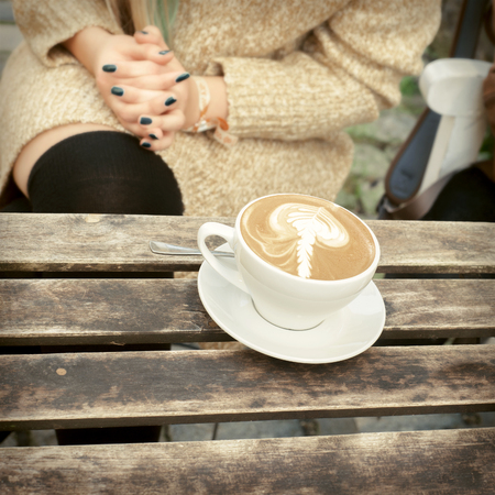 cup of coffee latte on a wooden table at the cafe outside