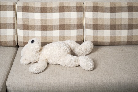 White Teddy bear is laying on the sofaの写真素材