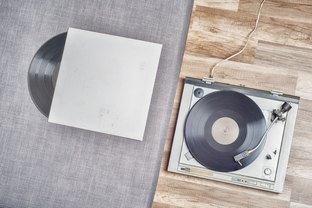 Old vinyl record in a paper case and turntable on the wooden floorの写真素材