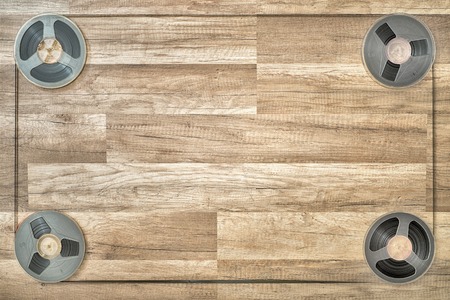 Four vintage magnetic audio reels in the corners on the grunge wooden floorの写真素材