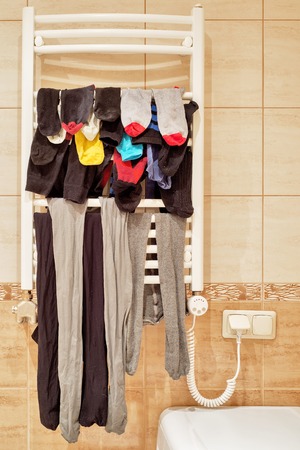 Lot of socks and leggings drying on bathroom radiatorの写真素材