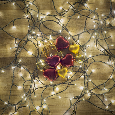 Dark Colorful Christmas background, garland lights on wooden floor with glitter baubles and tinselの写真素材