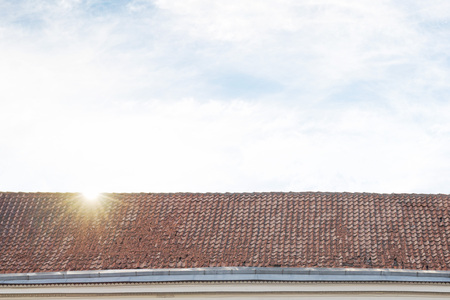 cloudy blue sky with sun flares, tiled roof top background