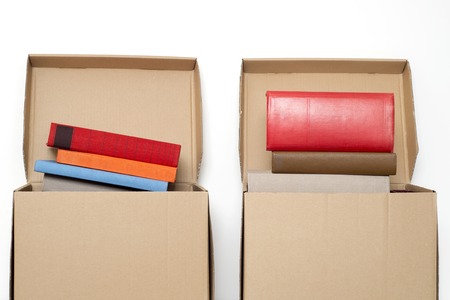 cardboard boxes full of books near the white wall