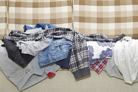 Lot of wrinkled clothes lying on sofaの写真素材
