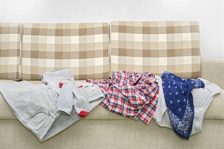 Lot of wrinkled clothes lying on sofaの写真素材