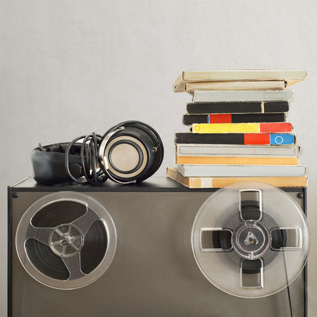 Vintage magnetic audio reels and headphones on the analog tape recorder near the stucco wallの写真素材