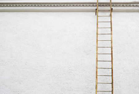 White stucco wall of historical building with metal fire escape ladderの写真素材