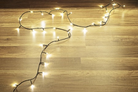 Dark christmas background, garland lights on wooden floorの写真素材