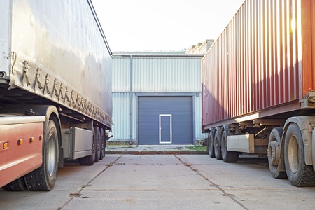 Two trucks standing near the blue garage doorの写真素材