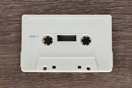 Vintage white audio cassette tape on brown wooden background. Side 1の写真素材
