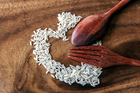 rice with spoon and fork on old wooden tableの写真素材
