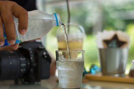 Hand pouring cold drinking water in to the glassの写真素材