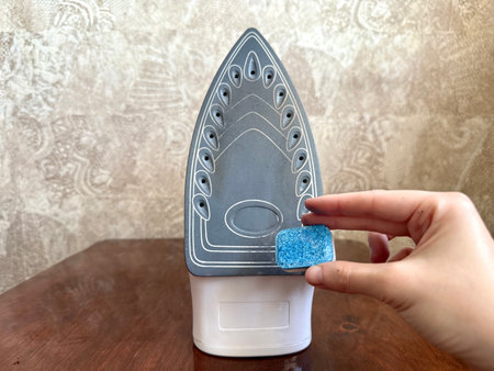 A cleaning hack for removing burnt residue from an iron soleplate using a dishwasher tablet.の写真素材