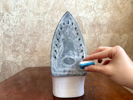A cleaning hack for removing burnt residue from an iron soleplate using a dishwasher tablet.の写真素材