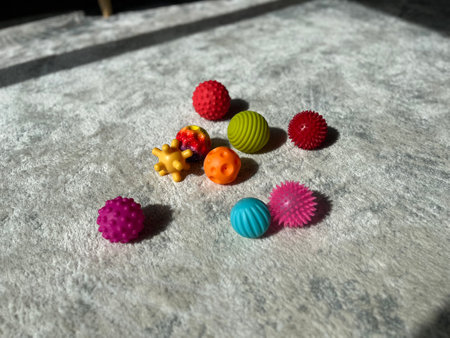 A collection of colourful sensory balls for children scattered on a soft carpet in a sunlit room.の写真素材