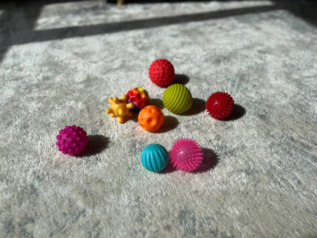 A collection of colourful sensory balls for children scattered on a soft carpet in a sunlit room.の写真素材