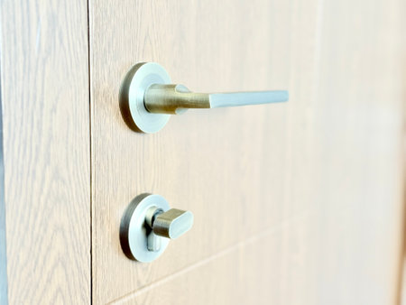 A close-up of a wooden door with a modern metal handle and thumb-turn lock.の写真素材