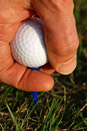 Anticipating a perfect drive as golfer puts his ball and tee in placeの写真素材
